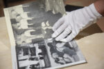 Osoba przegląda publikację z czarno-białymi zdjęciami; ma na sobie białą rękawiczkę; w kadrze zdjęcia jest tylko publikacja i dłoń przeglądającego.